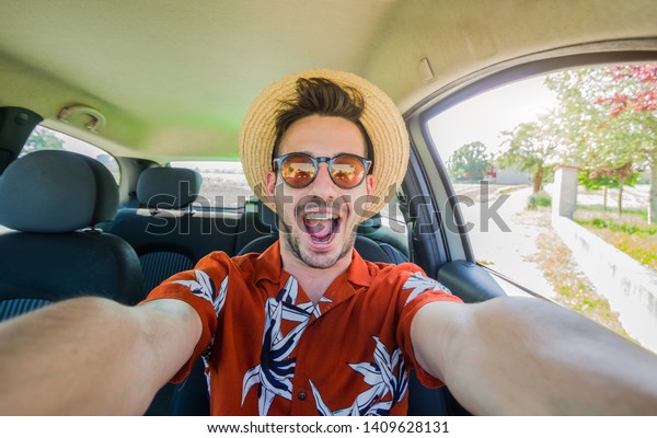 Happy young driver taking a selfie on his rental\
car at vacation