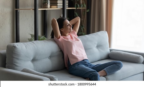 Happy Young Ethnic Girl Sit Relax On Couch In Living Room Breathe Fresh Air At Home, Smiling Arabic Indian Young Woman Rest On Sofa Breathe Fresh Air, Enjoy Lazy Weekend, Stress Free, Peace Concept