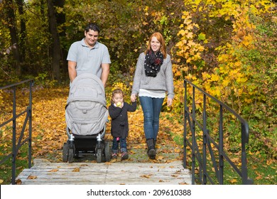 Happy Young Family In Autumn Making Together A Walk In The Nature.