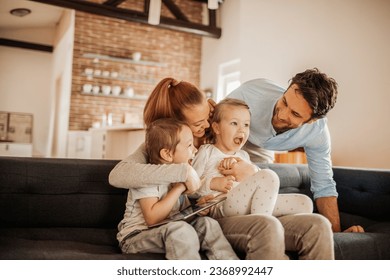 Happy young family bonding and having fun on the couch at home - Powered by Shutterstock