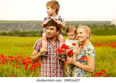 Happy young family with children resting outdoors in poppies field