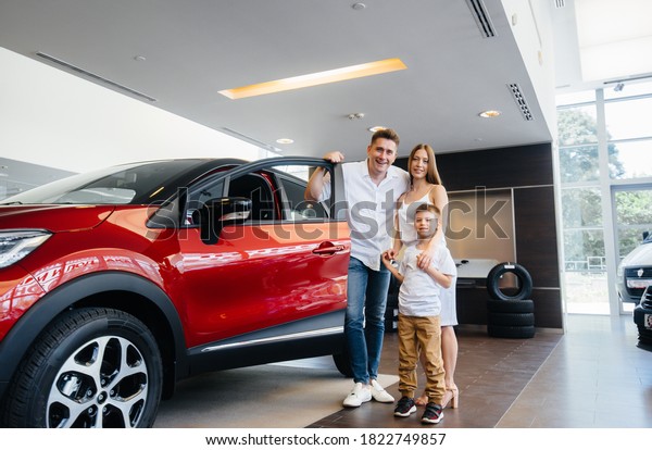 A happy young family chooses and buys a\
new car at a car dealership. Buying a new\
car