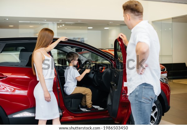 A happy young family chooses and buys a\
new car at a car dealership. Buying a new\
car