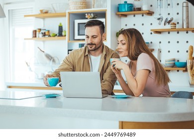 Happy young family couple bonding laughing using laptop looking at screen sit at table, smiling husband and wife buying choosing goods online doing internet shopping order with delivery at home - Powered by Shutterstock