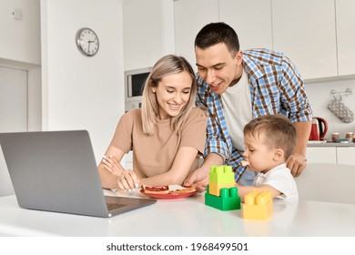 Happy Young Family Couple With Kid Son Eating Toasts With Jam Using Laptop In Kitchen. Cute Small Child Boy And His Parents Enjoying Breakfast Snack While Working From Home On Computer.