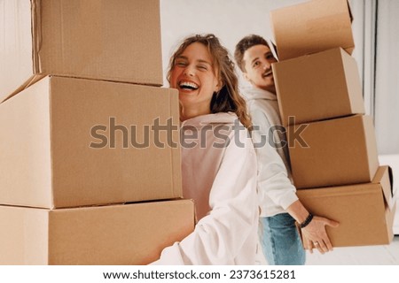 Happy young family couple man and woman moving with cardboard boxes to their new home apartment.