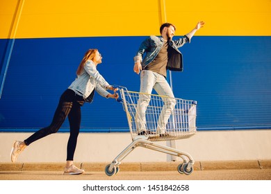 Happy Young Family Couple Run With Cart To Store Supermarket For Shopping. Lifestyle Concept.