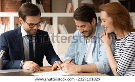 Happy young family couple signing paper contract with professional realtor lawyer banker at office meeting. Satisfied with deal smiling millennial clients making agreement with financial advisor.