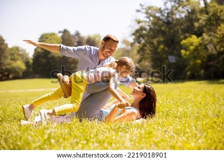 Happy young family with cute little daughter having fun in park on a sunny day