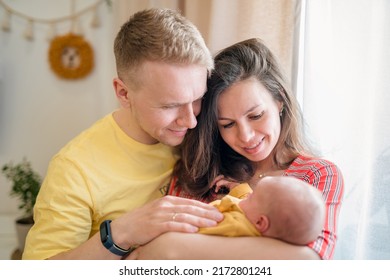 Happy Young Family With Dad, Mom And Newborn Baby In The Baby's Room