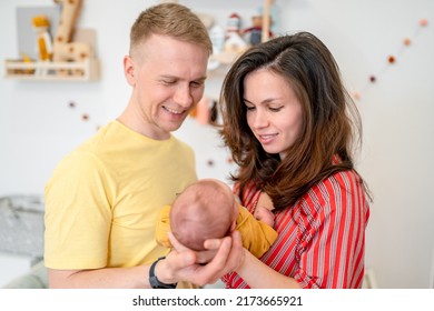 Happy Young Family With Dad, Mom And Newborn Baby In The Baby's Room