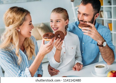 Happy Young Family Eating Chocolate Glazed Donuts