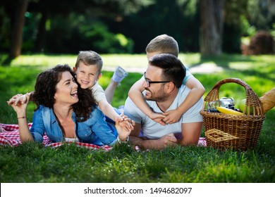 Happy Young Family Enjoying Picnic In Nature