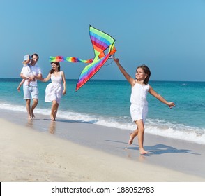 Happy Young Family With Flying A Kite On The Beach