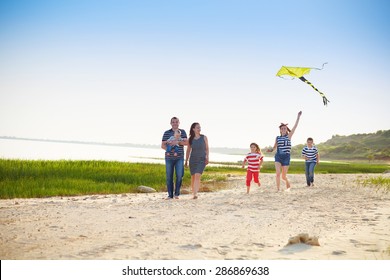 Happy Young Family With Flying A Kite On The Beach. Summer Vacation