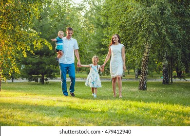 Happy young family of four people walking and having fun in the park - Shutterstock ID 479412940