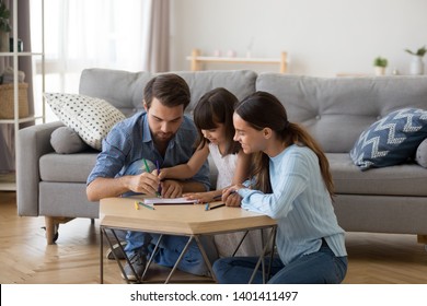 Happy Young Family Have Fun Sit On Floor In Living Room Draw With Coloring Pencils Together, Cute Preschooler Girl Enjoy Weekend With Parents Painting, Involved In Creative Learning With Mom And Dad