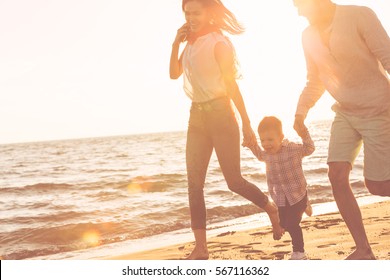 Happy Young Family Have Fun On Beach Run And Jump At Sunset