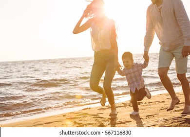 Happy Young Family Have Fun On Beach Run And Jump At Sunset