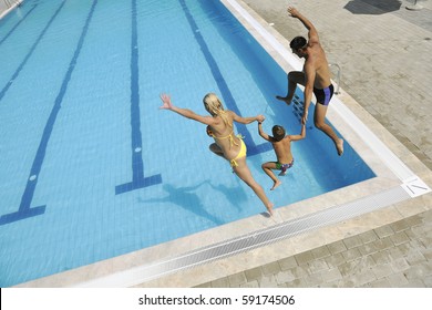 Happy Young Family Have Fun On Swimming Pool  At Summer Vacation Running And Jumping In The Pool