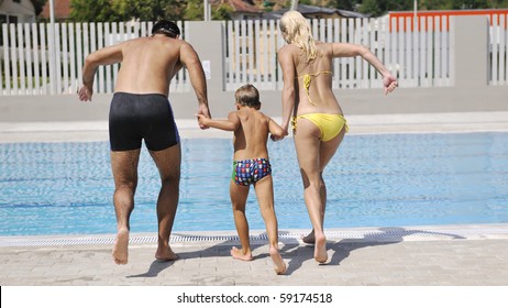 Happy Young Family Have Fun On Swimming Pool  At Summer Vacation Running And Jumping In The Pool