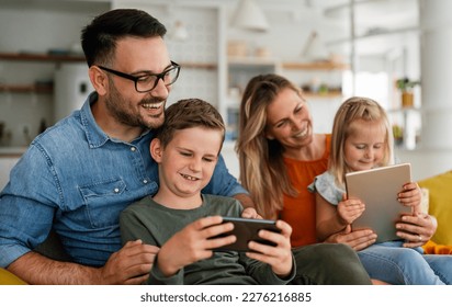 Happy young family having fun time at home. Parents with children using digital device. - Powered by Shutterstock