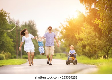 Happy Young Family Having Fun Outside On The Street Of A Village