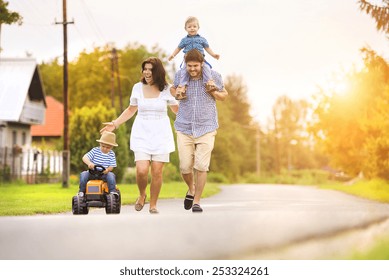 Happy Young Family Having Fun Outside On The Street Of A Village