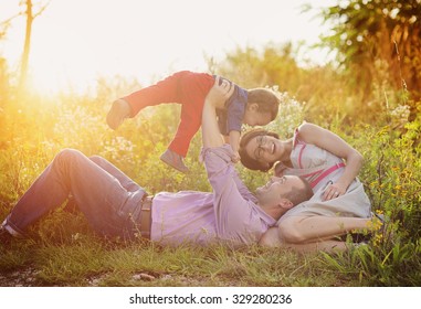 Happy Young Family Having Fun Outside In Summer Nature