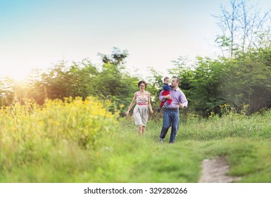 Happy Young Family Having Fun Outside In Summer Nature