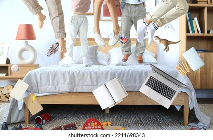 Happy young family jumping on the bed. The concept of happy time, success and surprise. - Shutterstock ID 2211698343