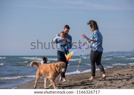 happy young family with kids having fun with a dog and  kite at beach during autumn day