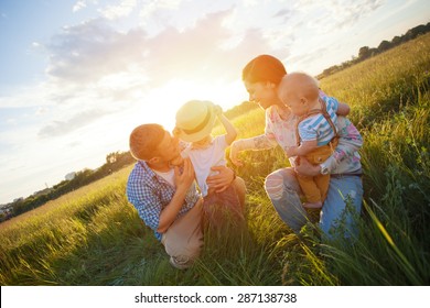 Happy Young Family With Kids Playing In The Park (intentional Sun Glare, Lens Focus On Son With Hat)