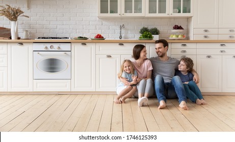 Happy young family with little children sit on warm wooden floor in new modern design kitchen, overjoyed parents with excited small kids relax rest in own renovated apartment, moving concept - Shutterstock ID 1746125393