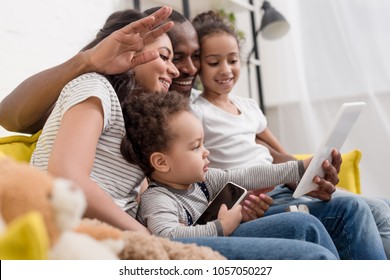 Happy Young Family Making Video Call With Tablet At Home