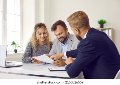 Happy young family at meeting in office signs document on purchase of real estate or loan agreement. Head of bank, realtor or financial advisor submits contract and indicates place of its signing.. - Shutterstock ID 2150526559