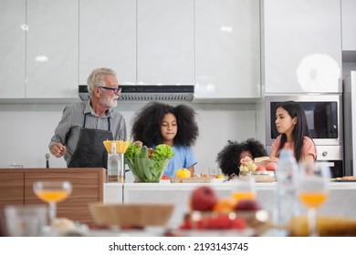 Happy Young Family With Mom, Dad And 2 Young Children Cooking Together. Kind Parents Teach Their Lovely Daughters How To Cook Healthy Meals For Free Space.