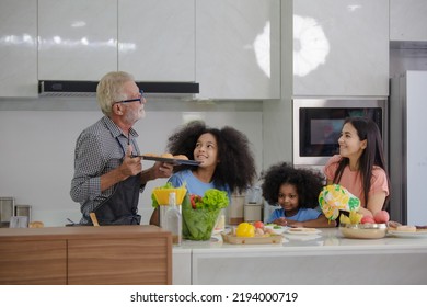 Happy Young Family With Mom, Dad And 2 Young Children Cooking Together.