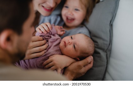 Happy Young Family With Newborn Baby And Little Girl Enjoying Time Together At Home.