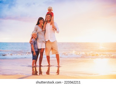 Happy Young Family On The Beach At Sunset