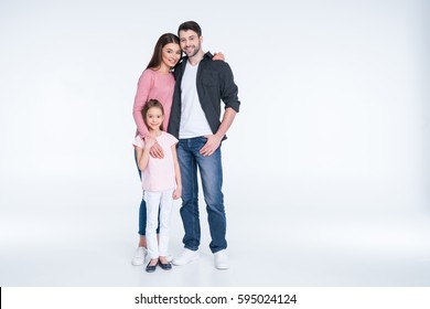 Happy Young Family With One Child Standing Embracing And Smiling At Camera Isolated On White