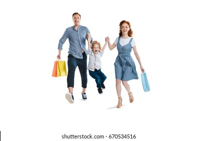 Happy Young Family With One Child Holding Shopping Bags And Smiling At Camera Isolated On White 