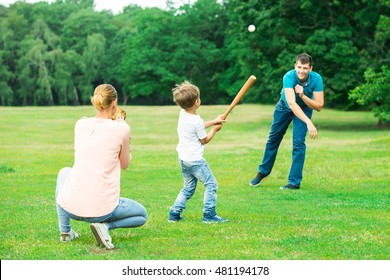 Happy Young Family Playing Baseball At Park