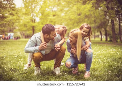 Fröhliche junge Familie, die im Park zusammen spielt.