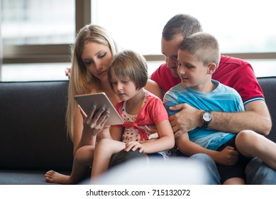 Happy Young Family Playing Together with tablet at home sitting on the sofa - Shutterstock ID 715132072