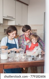 Happy Young Family Preparing Dough At Messy Kitchen