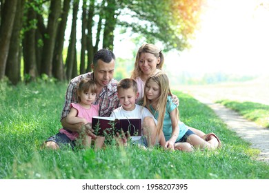 Happy Young Family Reading The Bible In Nature