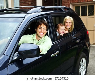 Happy Young Family Sitting In Black Car Looking Out Windows