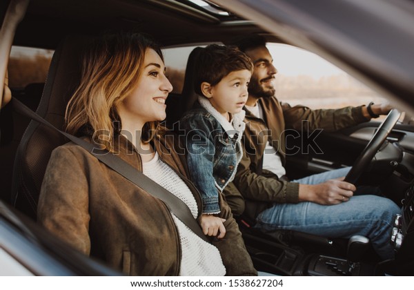 Happy young family\
sitting in the car.