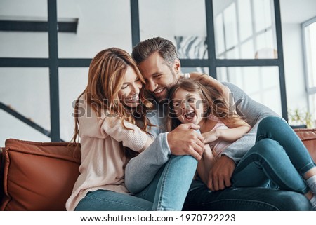 Happy young family smiling and embracing while bonding together at home